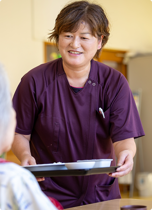 笑顔で食事を運ぶ介護スタッフ